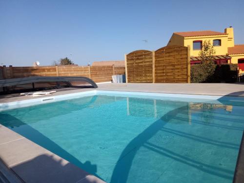une piscine avec de l'eau bleue dans une cour arrière dans l'établissement Maison 3 chambres avec piscine privée et jardin clos - FR-1-197-617, à Les Sables-dʼOlonne