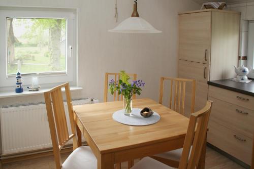 Una mesa de comedor con un jarrón de flores encima. en Ferienwohnung Im Landhaus, en Stelle-Wittenwurth