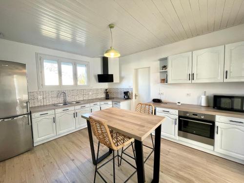 une cuisine avec des armoires blanches et une table en bois dans l'établissement Maison rénovée 3 chambres, proche centre et plage, jardin, parking - FR-1-231-332, à Bretignolles-sur-Mer