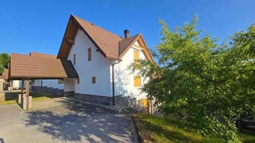 a small white church with a brown roof at Komforna planinska kuća za odmor in Mrkopalj