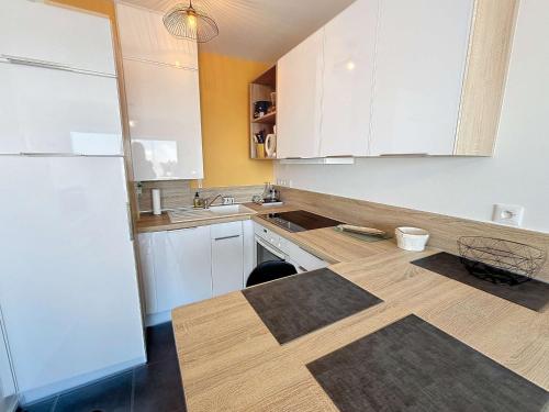 une cuisine avec des armoires blanches et un comptoir en bois dans l'établissement Appartement cosy avec balcon, port de Granville, 2 pers. - FR-1-361-550, à Granville