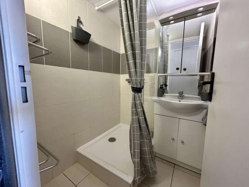 La salle de bains est pourvue d'un rideau de douche et d'un lavabo. dans l'établissement Maison 3 pièces près de la plage avec climatisation et parking - Saint Cyprien - FR-1-225D-222, à Saint-Cyprien