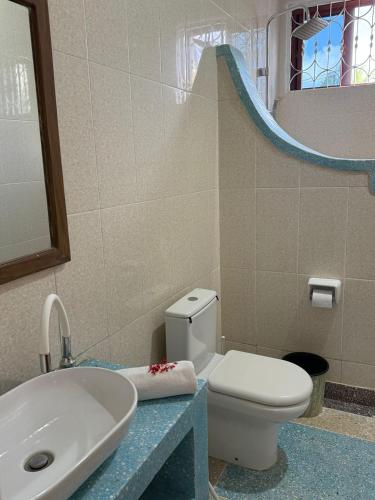a bathroom with a white toilet and a sink at Paje White House in Paje