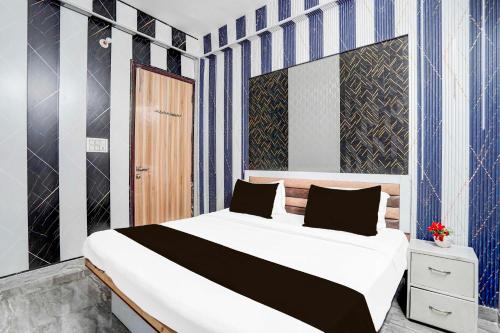 Collection O Sector 121 Gaur City Mall Noida Royal FNG في نويدا: غرفة نوم بسرير كبير عليها شرائط زرقاء وبيضاء