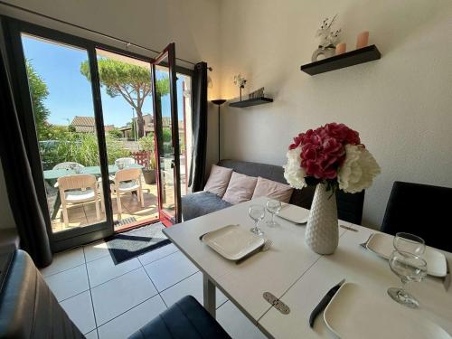 une table blanche avec un vase de fleurs sur elle dans l'établissement Maison 3 pièces près de la plage avec climatisation et parking - Saint Cyprien - FR-1-225D-222, à Saint-Cyprien