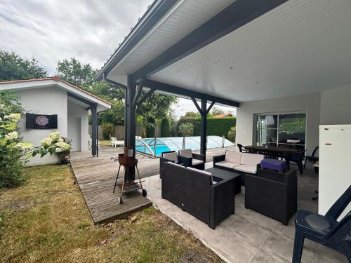 d'une terrasse couverte avec des canapés et une table. dans l'établissement Maison Familiale à Biscarrosse avec Piscine et Parking - FR-1-319-617, à Biscarrosse