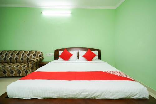 a bedroom with a bed with red pillows and a couch at Hotel O Infopark Kochi Malabar Plaza Residency in Ernakulam