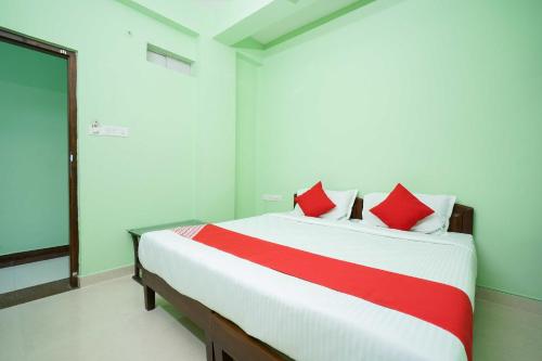 a bedroom with a large bed with red pillows at Hotel O Infopark Kochi Malabar Plaza Residency in Ernakulam