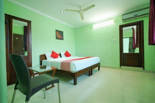 a bedroom with a bed and a chair and a mirror at Hotel O Infopark Kochi Malabar Plaza Residency in Ernakulam