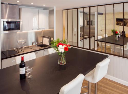 - une cuisine avec une table, une bouteille de vin et des fleurs dans l'établissement Superbe Duplex en Hypercentre avec Rooftop et Climatisation, à Bordeaux