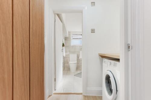 a bathroom with a washer and dryer in a room at LUX 1 Bed Flat next to Station in Tooting in London