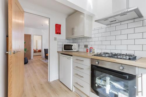 a kitchen with a stove and a microwave at LUX 1 Bed Flat next to Station in Tooting in London