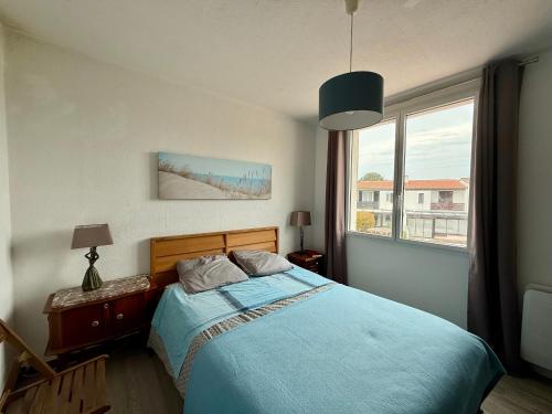 une chambre avec un lit bleu et une fenêtre dans l'établissement Maison avec jardinet proche plage et parking - FR-1-652-58, à Saint-Jean-de-Monts