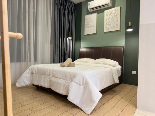 a bedroom with a large white bed with green walls at Manhattan Suites, Itcc in Penampang
