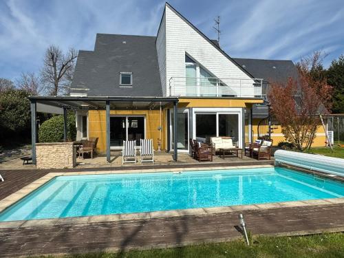 une maison avec une piscine devant une maison dans l'établissement Villa récente 4 chambres, piscine chauffée à Bavent - FR-1-487-380, à Bavent