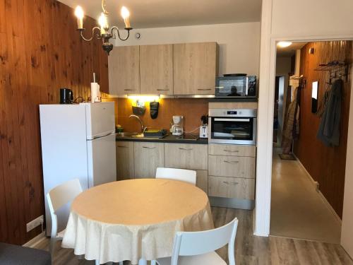 une cuisine avec une table et un réfrigérateur blanc dans l'établissement Appartement central à Super Besse, 2 chambres, proche pistes - FR-1-814-11, à Besse-et-Saint-Anastaise