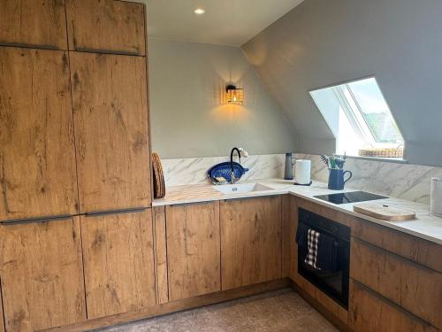 a kitchen with wooden cabinets and a sink and a window at Appartement Duplex 2 Pièces Centre-Ville avec Balcon et Internet Inclus - FR-1-487-383 in Cabourg