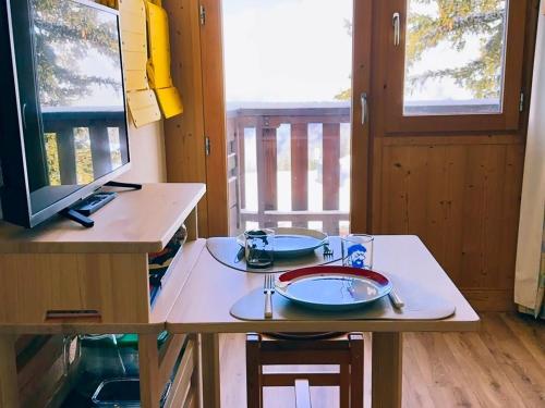 une table avec des assiettes et des ustensiles dessus dans l'établissement Studio ski-in/ski-out pour 2 personnes avec balcon ensoleillé - FR-1-275-224, à Montvalezan