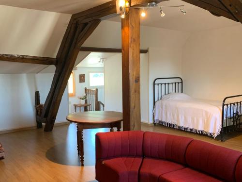 a living room with a red couch and a bed at Appartement au calme avec Wifi, en Brenne - FR-1-591-754 in Saint-Gaultier