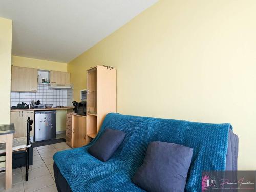 un salon avec un canapé bleu et une cuisine dans l'établissement Appartement T2 avec balcon, parking et proche port des Minimes - FR-1-825-67, à La Rochelle