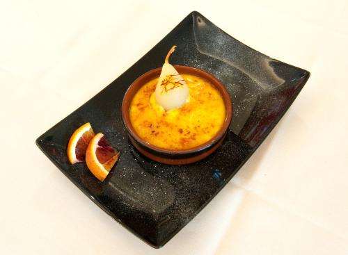 a black plate with a dessert with an orange slice at Hotel Bahnhof Haus in Chiasso