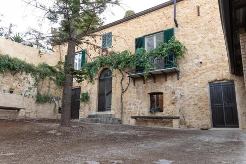 an old stone building with a tree in front of it at Villa dei Mandorli in Naro