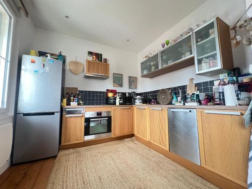 une cuisine avec des armoires en bois et un réfrigérateur en acier inoxydable dans l'établissement Bel Appartement T2 Près de la Plage - Idéal pour 4 Personnes - FR-1-474-272, à Arcachon