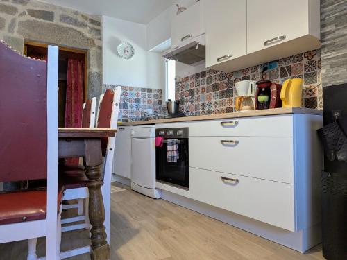 a kitchen with white cabinets and a table in it at Séjour rustique proche des Estables et du Puy-en-Velay - FR-1-582-533 in Saint-Front