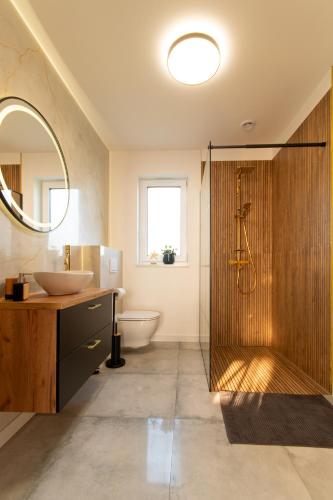 a bathroom with a sink and a toilet and a mirror at Domki całoroczne Pogodna Fala, Grzybowo in Grzybowo