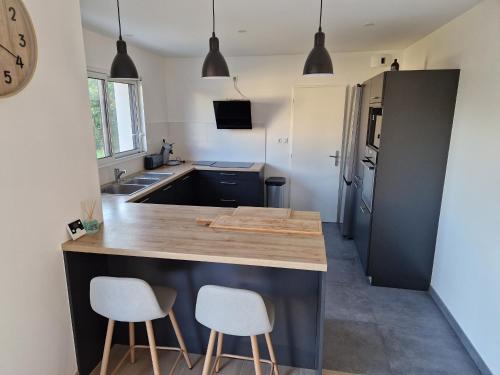 une cuisine avec un comptoir et deux tabourets sur un îlot de cuisine dans l'établissement Maison moderne pour 8 pers. à 600m de la plage avec grand jardin - FR-1-639-140, à Sarzeau