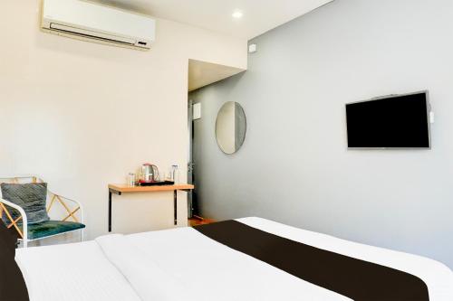 a bedroom with a bed and a tv on the wall at Super Townhouse MG Road Pune in Pune