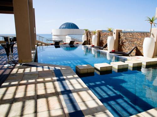 
a large swimming pool with a balcony overlooking the ocean at Premier Hotel East London ICC in East London
