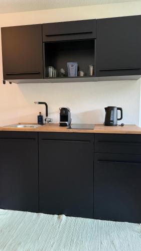 a kitchen with black cabinets and a sink at KREATIVPAUSE Workation in Bayern - Stilvolle Workation-Unterkunft mit Arbeitsplatz & Naturblick in Bayern in Rötz