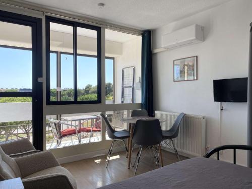 un salon avec une table, des chaises et des fenêtres dans l'établissement Studio vue parc avec climatisation - FR-1-553-305, à Balaruc-les-Bains