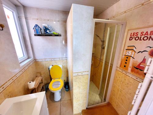 La salle de bains est pourvue d'une douche et de toilettes jaunes. dans l'établissement Maison de pêcheur moderne avec terrasse, proche mer et commerce - Barbecue - WIFI Gratuit - FR-1-92-950, à Les Sables-dʼOlonne