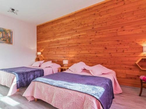 two beds in a room with a wooden wall at Gîte paisible dans forêts avec vélos et randonnées, animaux admis - FR-1-583-503 in Montigny-les Cherlieux