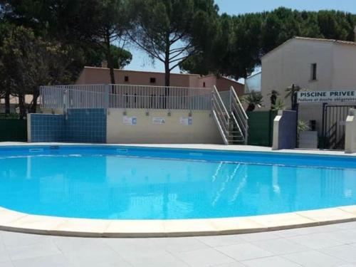 une grande piscine bleue devant un immeuble dans l'établissement T2 Climatisé avec Piscine et Parking, Cap d'Agde, près de la plage - FR-1-607-226, au Cap d'Agde