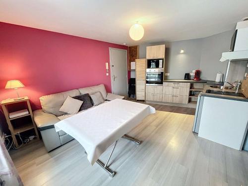 - un salon avec une table blanche et un mur rouge dans l'établissement Appartement lumineux à Jullouville, proche plage, avec parking et wifi gratuit - FR-1-361-565, à Jullouville