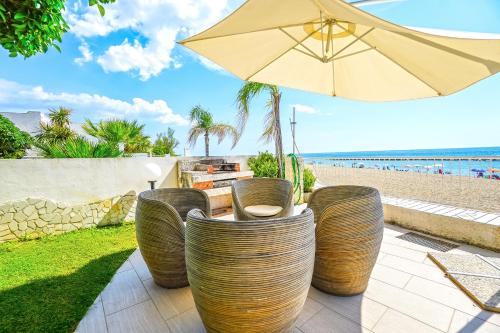patio z krzesłami, parasolem i plażą w obiekcie Villa di Lusso sul Mare a Diamante - Villa Ventre w mieście Belvedere Marittimo