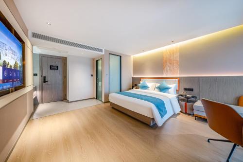 a bedroom with a large bed and a flat screen tv at Kunming Meihao Lizhi Hotel Cuihu Park Yunnan University Hospital Branch in Kunming