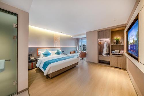 a bedroom with a large bed and a flat screen tv at Kunming Meihao Lizhi Hotel Cuihu Park Yunnan University Hospital Branch in Kunming