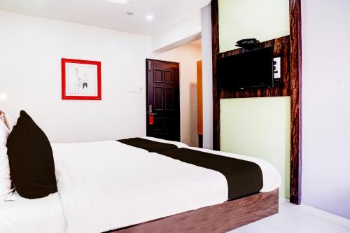 a bedroom with a bed and a tv on the wall at Super Townhouse OAK Kopar Khairane Navi Mumbai Formerly IVY Hotel in Navi Mumbai