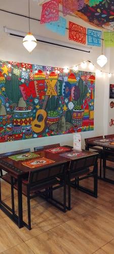 due tavoli in una stanza con un dipinto sul muro di W District hostel a Bangkok