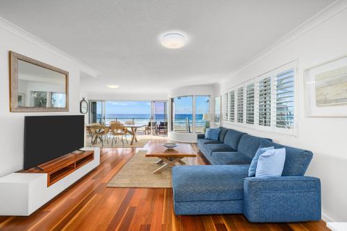 a living room with a blue couch and a tv at BEACHFRONT Beauty! in Gold Coast