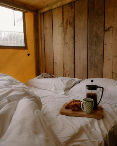 a bed with a tray of food and a cup of coffee at Damselfly Riverdale Yorkshire in West Tanfield