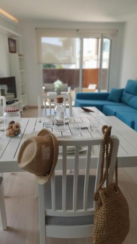 a white dining room table with a hat and a purse at Apartamento TURQUESA in O Porto de Espasante