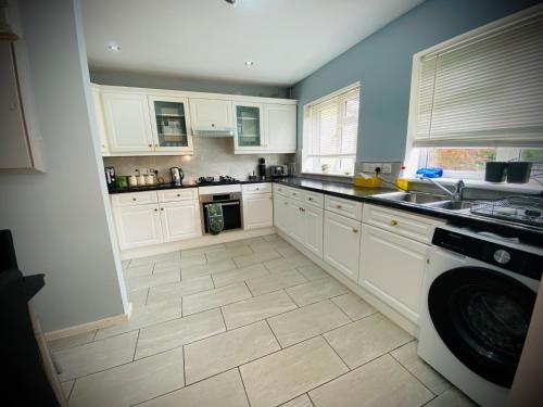 a kitchen with white cabinets and a tile floor at Modern-PetFriendly-privateGarden-Family-20MinToLDN in Stevenage