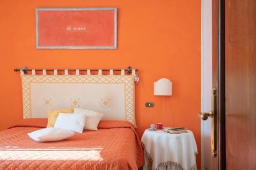a bedroom with a bed with an orange wall at VILLA COSTANZA 6, Emma Villas in Fivizzano