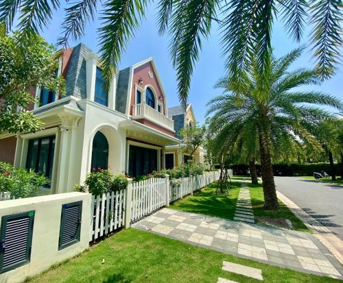 a house with a white fence and a palm tree at Wonderland Royal Mansions Ho Tram in Xuyên Mộc