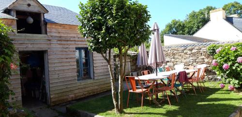 - une table et des chaises avec un parasol dans la cour dans l'établissement Maison familiale Groix, à Groix
